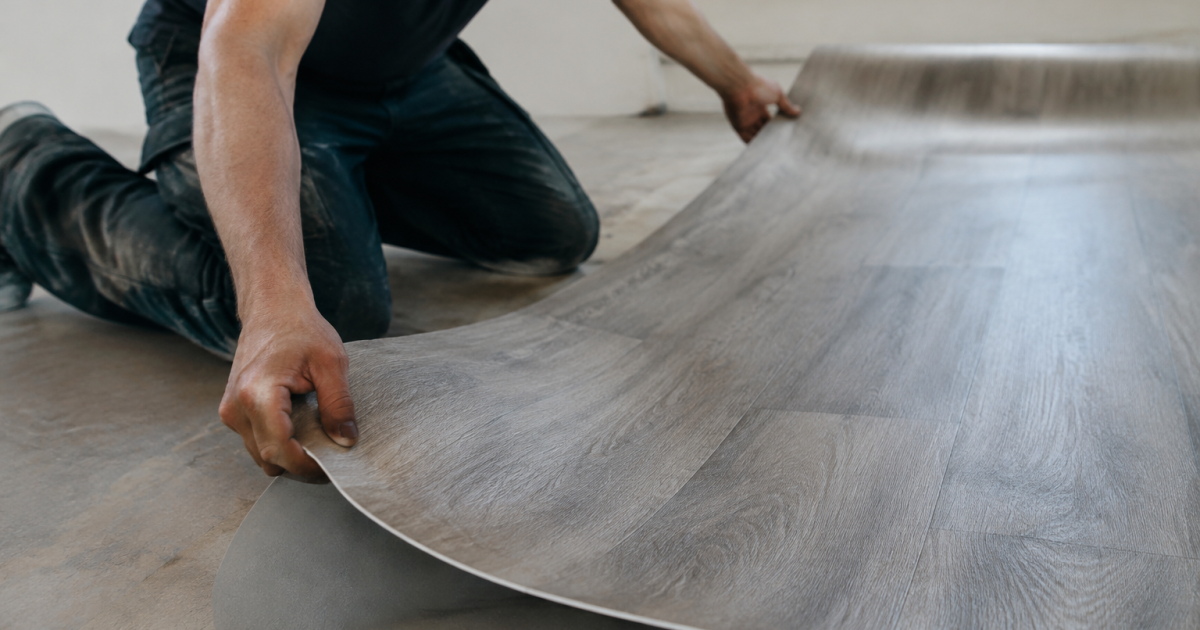 Mains etendant une feuille de vinyle sur plancher