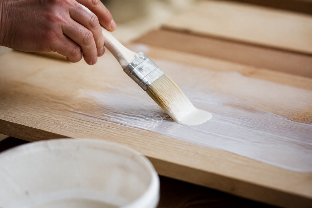 Pinceau etend substance blanche adhesive sur bois