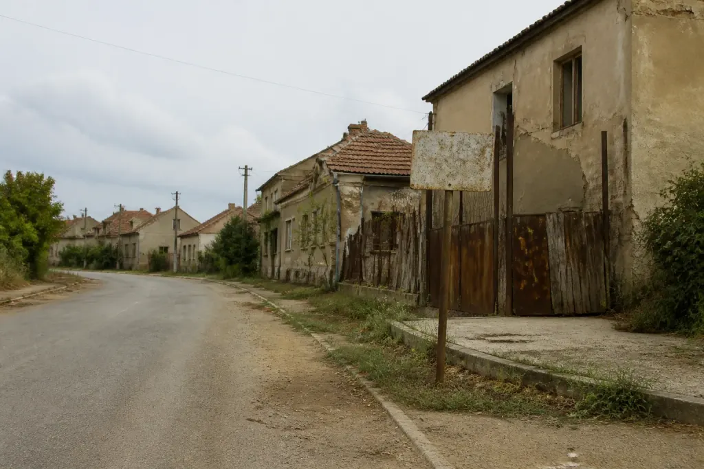 Route déserte bordée de maisons vides et panneaux abîmés