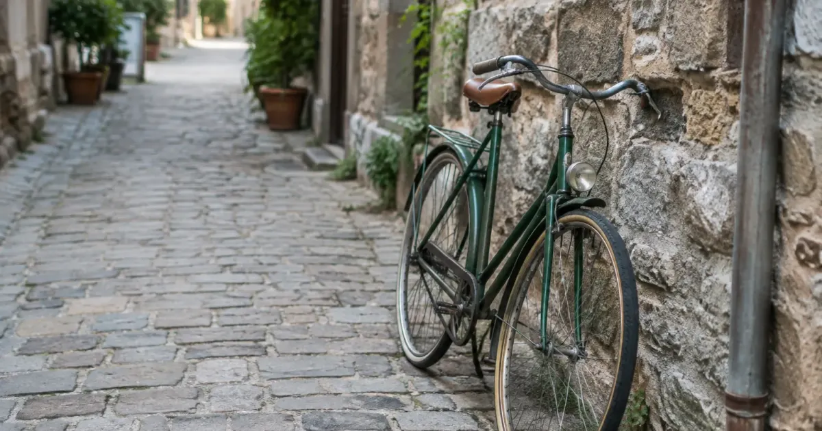 Ruelle pavee avec velo appuye contre mur en pierre